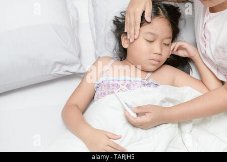 Mother measuring temperature of ill kid. Sick child with high fever laying in bed and mother holding thermometer, Healthy care concept Stock Photo