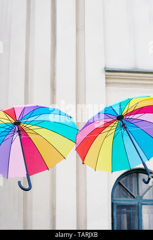 Colored bright rainbow umbrellas on the light old wall background Stock Photo