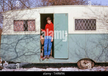 Archival 1960s just married young woman standing in doorway of dilapidated old caravan snow covered building site first marital home archive 60s the way we were in England UK Stock Photo