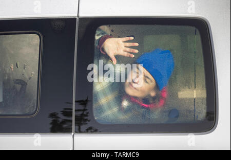 Woman sleeping in camper van waking up as the rising sun shines through the van window Stock Photo