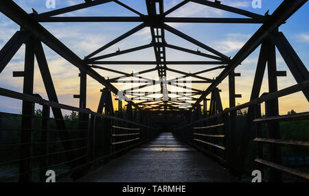 Empty metal bridge construction on the sunset sky background over the railroad highlighted by Sun in Kriviy Rih, Ukraine. Stock Photo