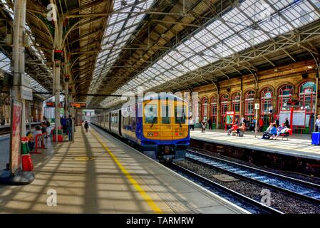Preston, United Kingdom - May 14, 2019: Preston railway station In north west England with train at platform and passengers some motion blurred on adj
