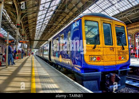 Preston, United Kingdom - May 14, 2019: Preston railway station In north west England with train at platform and passengers some motion blurred on adj