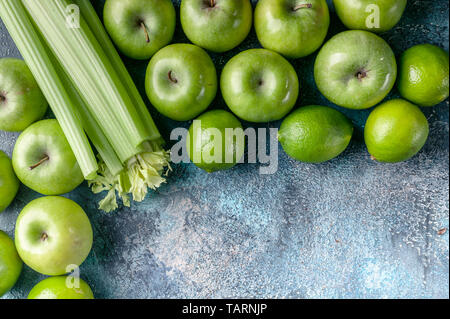 Green apples, celery and limes on a concrete background. Detox program, diet plan, weight loss. Flat lay composition. Top view Stock Photo