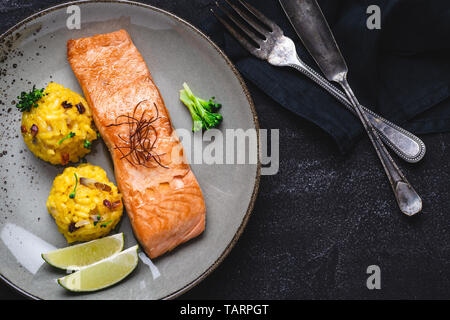 Grilled Salmon Fillets with Saffron Risotto and Lime on Dark Background Stock Photo