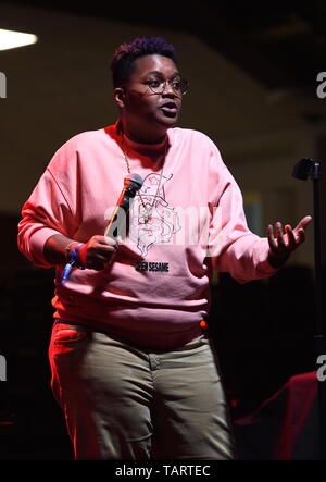 Comedian Sam Jay is shown performing on stage during a 'live' stand up concert appearance. Stock Photo