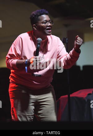 Comedian Sam Jay is shown performing on stage during a 'live' stand up concert appearance. Stock Photo