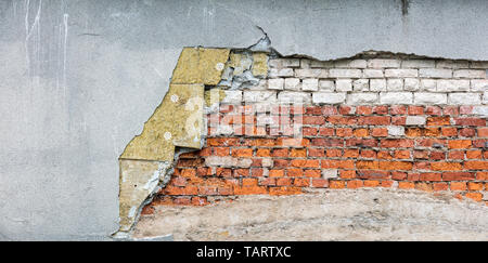 fragment of old destroyed wall with damaged bricks, insulation wool and rough stucco layer. house renovation concept Stock Photo