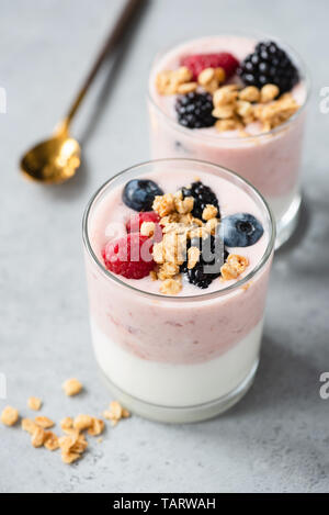 Yogurt with baked granola and berries in white ceramic plate on wooden ...