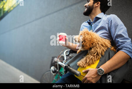 Handsome business man on street drinking coffee with dog Stock Photo