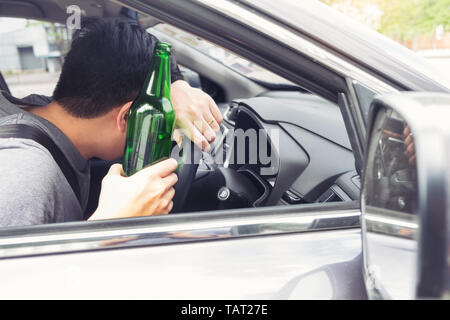 Don't Drink for Drive concept, Young Drunk man drinking bottle of beer or alcohol during driving the car dangerously. Stock Photo