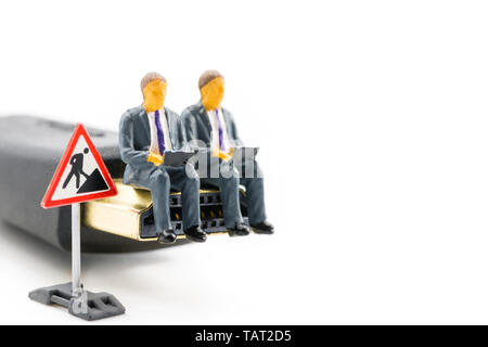 Macro shot on miniature figures as business men working on the laptop notebook sitting on HDMI plug, isolated on white background. Information technol Stock Photo