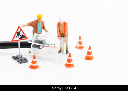 Macro shot on miniature figures as technicians working on the internet web network repair cable socket, isolated on white background. Information tech Stock Photo