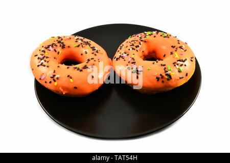 Orange donuts with sprinkles on black plate on white background Stock Photo