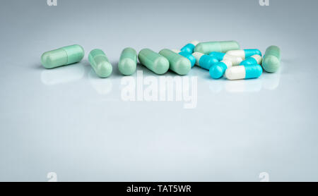 Herbal and drug interactions. Green and blue capsule pill on white background. Herbal medicine. Pharmaceutical industry. Pharmacy drugstore background Stock Photo