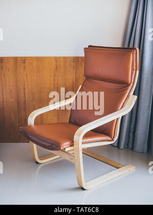 Brown leather on wooden armchair in hotel room. Modern armchair Layer-glued bent birch frame gives comfortable resilience. Stock Photo