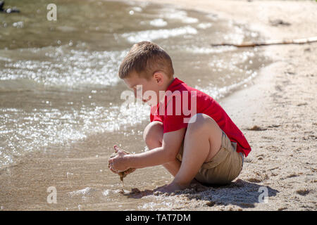 A young boy plays in the sand on the shores of Tenaya Lake in Yosemite National Park, California, USA. Stock Photo