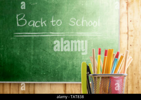 Pencils in basket container with green stapler with chalkboard background. Back to School concept Stock Photo
