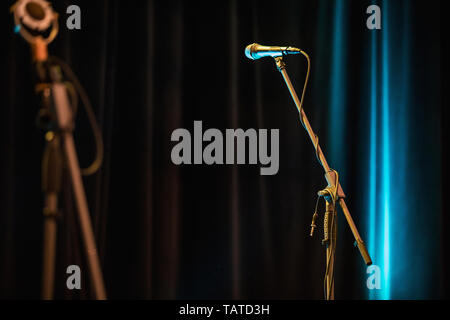 Microphone in focus against blurred background. Public performance on stage Microphone on stage against a background of auditorium. Stock Photo
