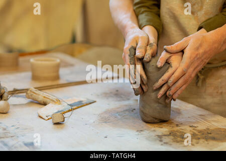 Man tightly pressing. Passionate couple dealing with wet piece of clay while connecting hands and showing their feelings Stock Photo