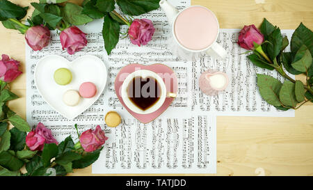 Feminine desk or workspace coffee break time overhead flatlay with sheet music and roses with copy space. Stock Photo