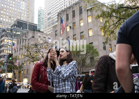 Two beautiful girls are taking photos and selfies in front of Rockefeller plaza. Stock Photo
