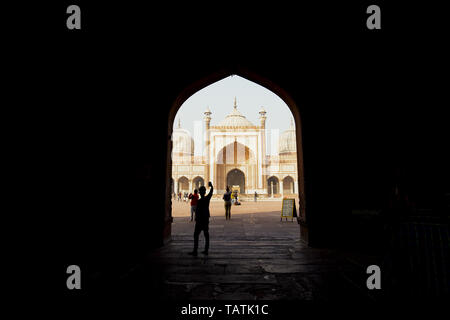 Some tourists are taking photos and selfies in front of the beautiful Jama Masjid in New Delhi during sunset. Stock Photo