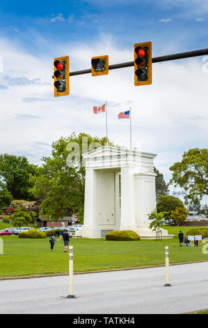 May 26, 2019 - Surrey, BC: Red traffic control light above road to border with Canada-USA Peace Arch Monument and park in background. Stock Photo