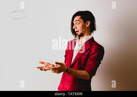 Portrait of young magician handling ropes and bandanas to do magic tricks, isolated on white. Stock Photo