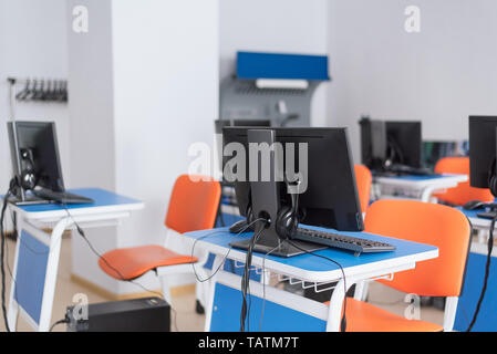 empty computer classroom with bright blue desks and orange chairs. teaching children programming. there is not anyone. Stock Photo