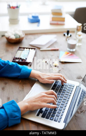 Hands of contemporary creative designer in blue blouse typing on laptop keypad while surfing in the net for creative pictures of footages Stock Photo