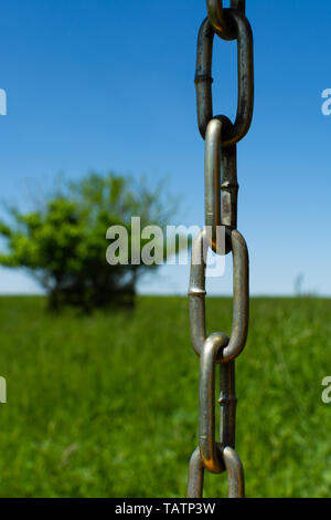 Silver chain with green grass and blue skies in the background. Stock Photo