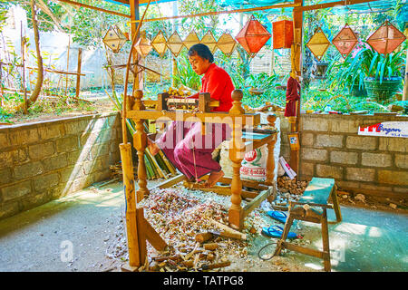PINDAYA, MYANMAR - FEBRUARY 19, 2018:  The woodworker produces the bamboo handles for paper parasols, using foot-operated wood turning lathe in tradit Stock Photo
