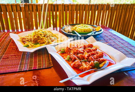 Enjoy the dinner in restaurant of tourist village - pork stew in spicy sauce, rice noodles with vegetables and sticky rice in banana leaf wrap, Nyaung Stock Photo