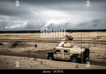 An Army Humvee drives alongside M1 Abrams tanks belonging to the 3rd Battalion 66th Armored Regiment, 1st Armored Brigade Combat Team, 1st Infantry Division, on a range in Trzebień, Poland during a live-fire training exercise, May 10, 2019. Soldiers from the 3-66 AR are deployed to Poland in support of NATO allies as part of Atlantic Resolve. (U.S. Army Photo by Sgt. Jeremiah Woods) Stock Photo
