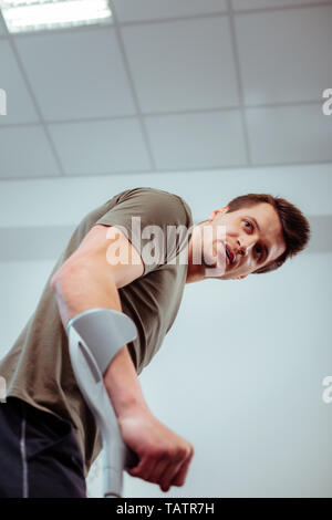 Problem with walking. Low angle of a handsome young man using crutches while walking Stock Photo