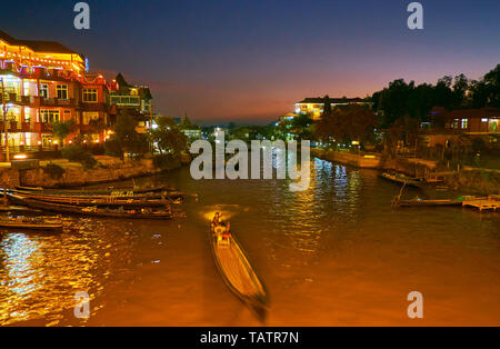The narrow canal of Inle lake is illuminated with bright lights of Nyaungshwe tourist village, Myanmar. Stock Photo