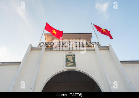 Ben Thanh Market (built in 1912-1914), the facade and the arch of the central entrance and two swaying Vietnamese flags. Stock Photo