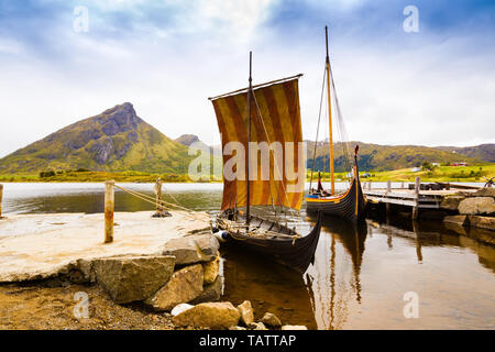 Landscape with viking boats at village small harbor, mountains and fjord in Lofoten islands, Norway. Stock Photo