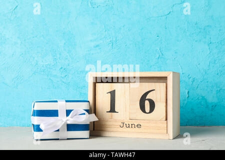 Wooden cubes calendar date June 16 and gift box on white table against color background, space for text Stock Photo