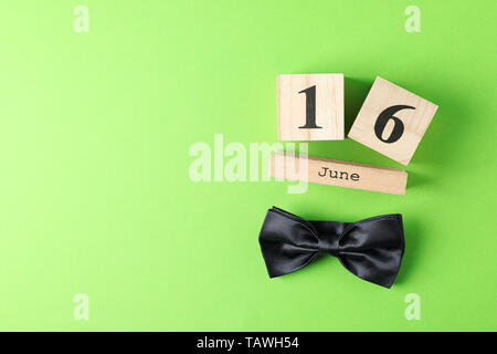 Wooden cubes calendar date June 16 and bow tie on color background, space for text Stock Photo