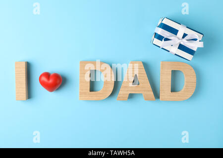 Inscription I love Dad made with wooden letters and red decorative heart, and gift box on color background, space for text Stock Photo