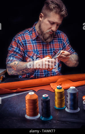Artist working with leather processing a leather workpiece . Stock Photo