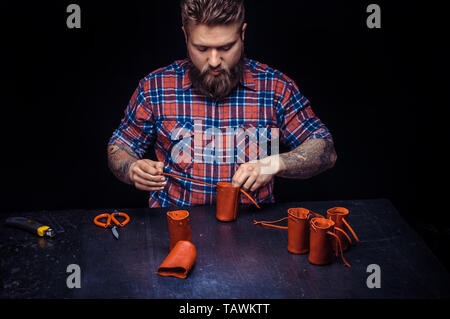 Artisan working with leather keen on one's business in his leather shop. Stock Photo