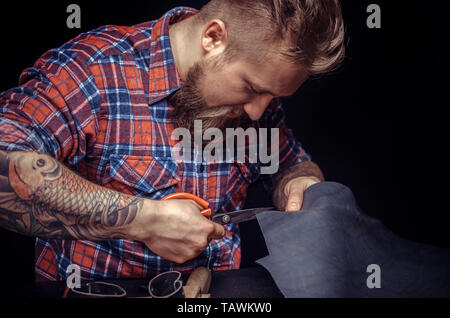 Craftsman working with leather making quality products at the leather shop. Stock Photo
