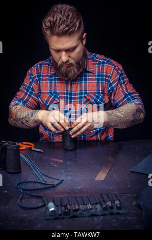 Tanner processes a workpiece from leather at his shop. Stock Photo