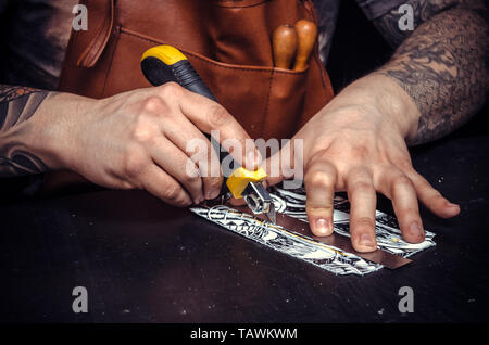 Worker of leather works with leatherwork in a workshop. Stock Photo