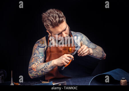 Handicraftsman wording with leather goods at the studio. Stock Photo
