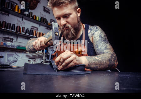Leather Currier cutting out leather goods . Stock Photo