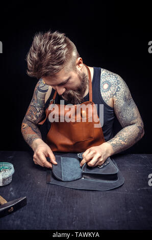 Leather Worker creating new leatherwork at his leather studio. Stock Photo
